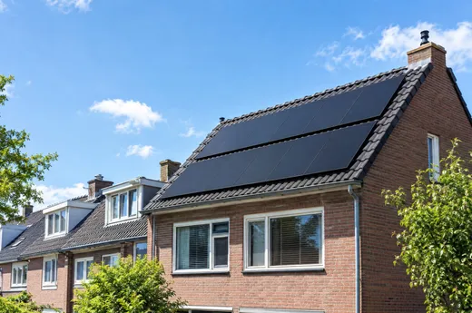 Twee rijen zwarte zonnepanelen op het pannendak van een rijtjeshuis